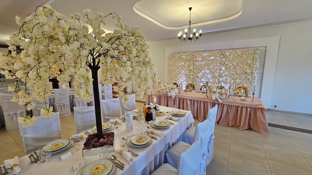 Dekoracja sali weselnej w stylu romantycznym — kwitnące drzewka i ściana kwiatowa